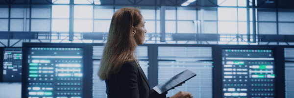 Digital solutions engineer checking system health on a tablet in a collaborative network operations hub