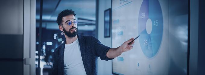 Business leader explains customer distribution metrics on a wall-mounted analytics dashboard