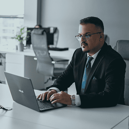 Office employee seated at a desk, typing on a laptop during focused work in a contemporary workplace setting.