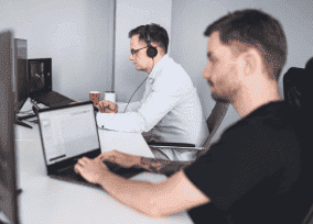 Innowise employees working on a digital product in a quiet office space with headphones and focus on screens