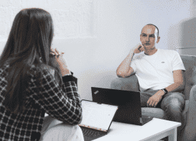 IT specialists holding a one-on-one meeting in a casual workspace with armchairs and a coffee table