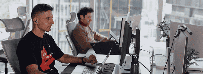 Software development team working on a project in a bright workspace with large windows overlooking the city skyline