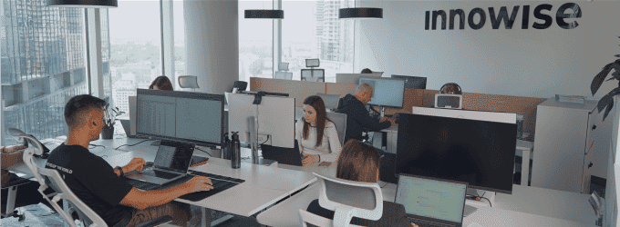 Innowise employees working on a digital product in a modern office with panoramic windows and company branding