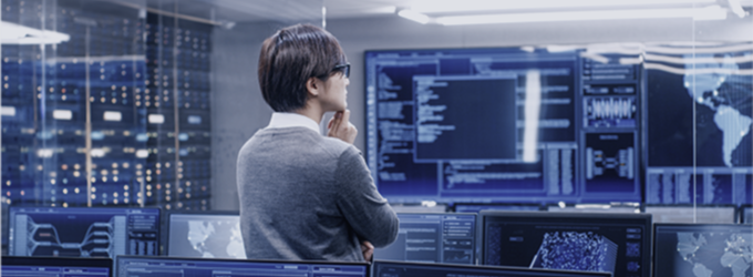 Analyst reviewing real-time global data and network activity in a high-tech operations center
