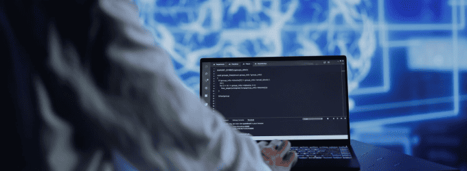 Software engineer reviewing source code on a laptop in a technology-driven environment
