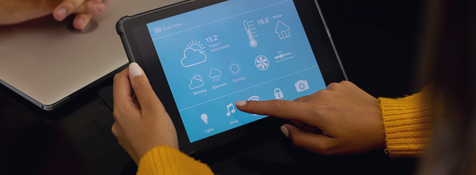 Resident uses tablet to manage connected devices like thermostat, lights, and door locks in a single app.
